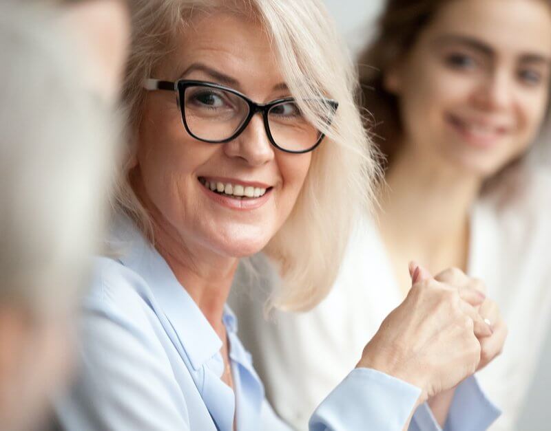 A woman with glasses attentively sitting in a meeting at Capital Premium Financing.