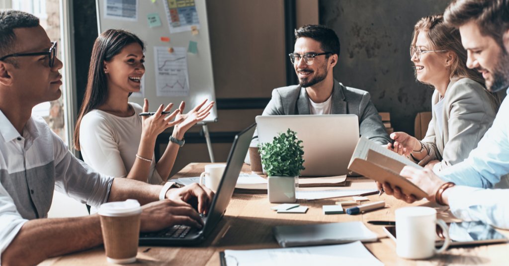 A group of professionals gathered around a table, each using laptops, engaged in discussion at Capital Premium Financing.