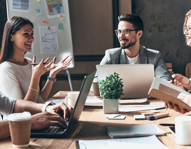 A group of professionals gathered around a table, each using laptops, engaged in discussion at Capital Premium Financing.