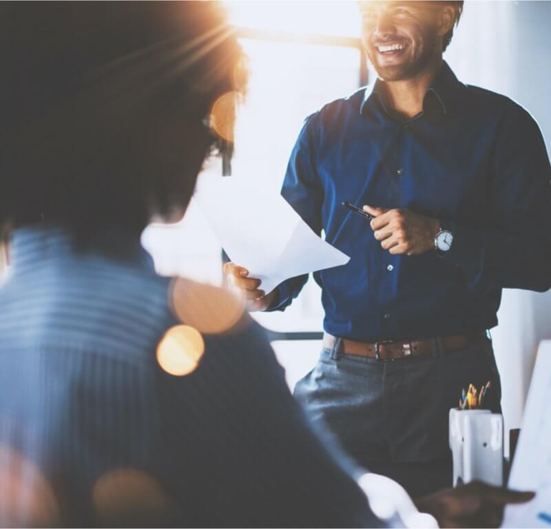 A man speaks to his colleagues in an office setting at Capital Premium Financing, engaging in a professional discussion.
