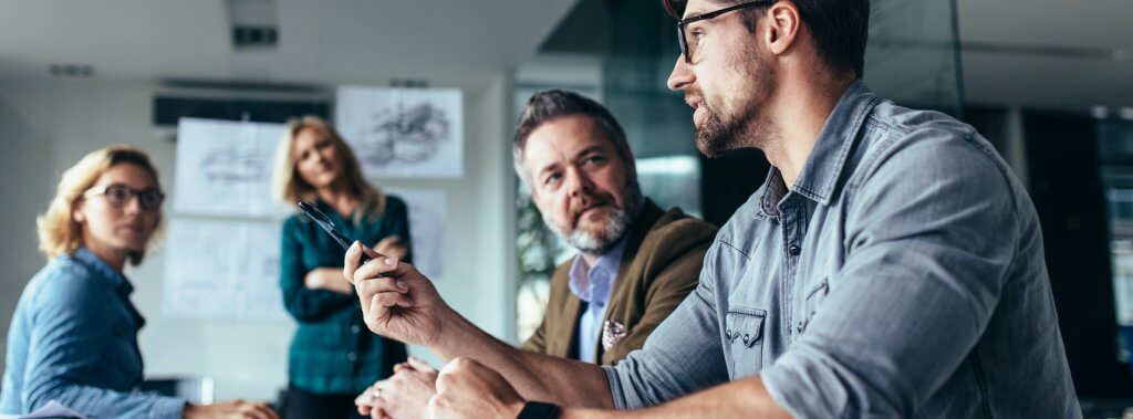 Smiling business professionals engaged in discussion around a conference table at Capital Premium Financing.