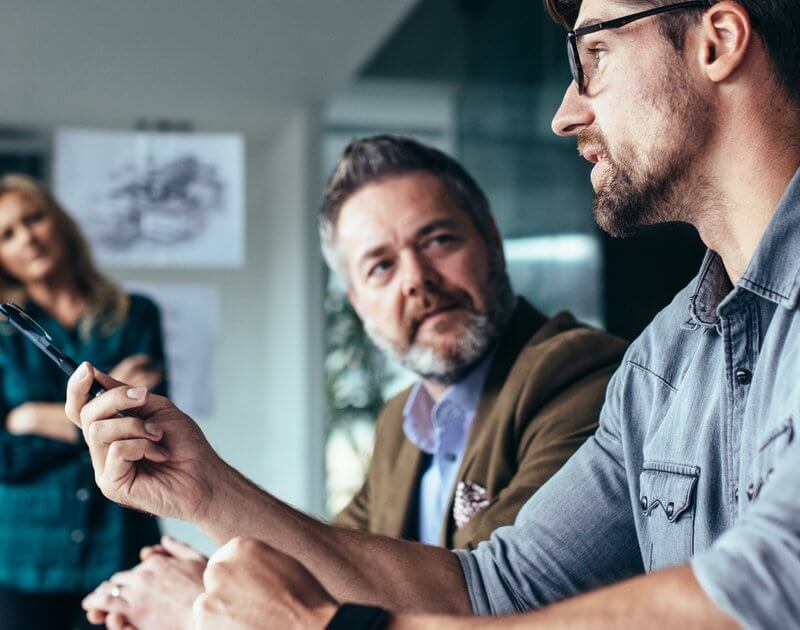 Smiling business professionals engaged in discussion around a conference table at Capital Premium Financing.
