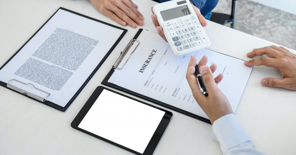 Business professionals from Capital Premium Financing signing documents and using a calculator in a collaborative office setting.