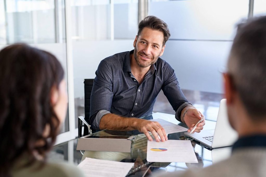 A man presents ideas to a woman and another man in a professional meeting