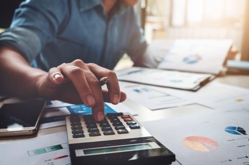 Businessman analyzing financial data with a calculator amid office documents
