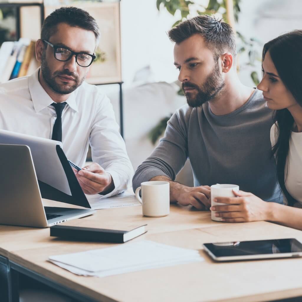 Three individuals seated at a table, collaborating on a laptop for Capital Premium Financing.