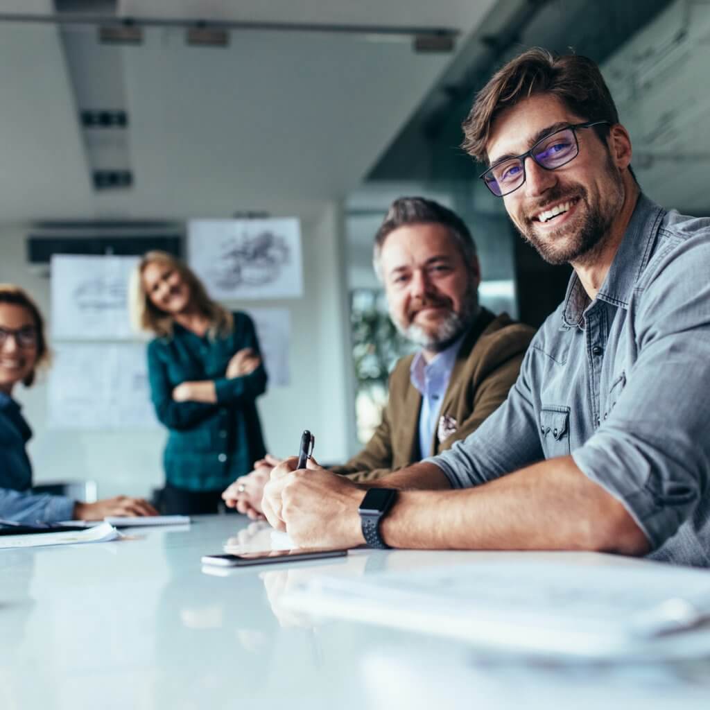 Smiling business professionals gathered around a conference table, discussing strategies for Capital Premium Financing.