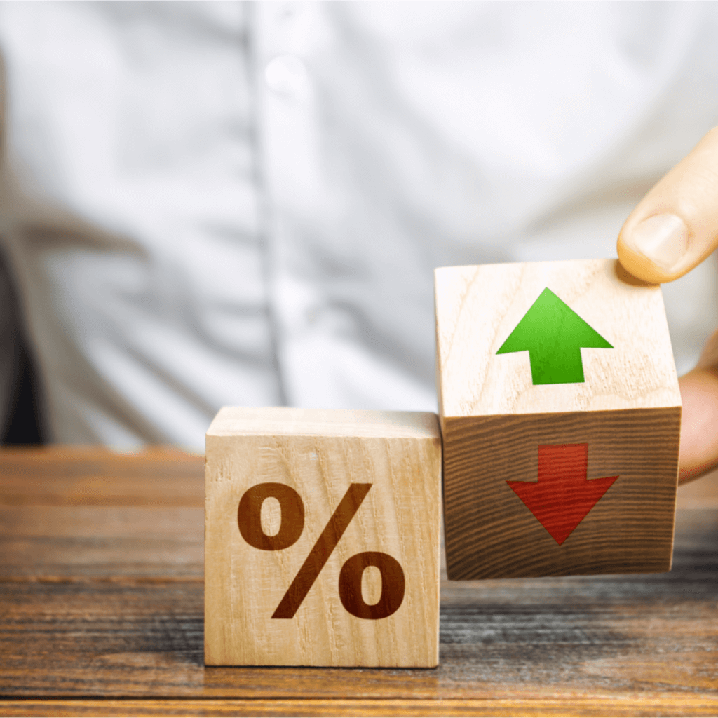 A person holds two wooden blocks, one with an upward arrow and the other with a downward arrow, representing Capital Premium Financing.