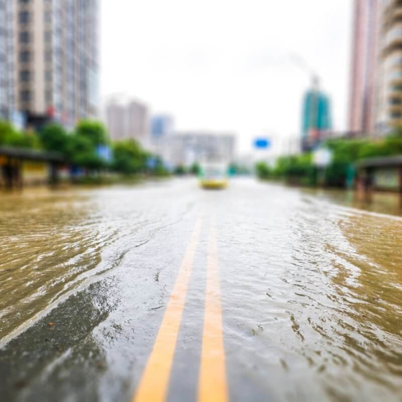 A flooded street featuring a prominent yellow line, with the logo of Capital Premium Financing in the corner.