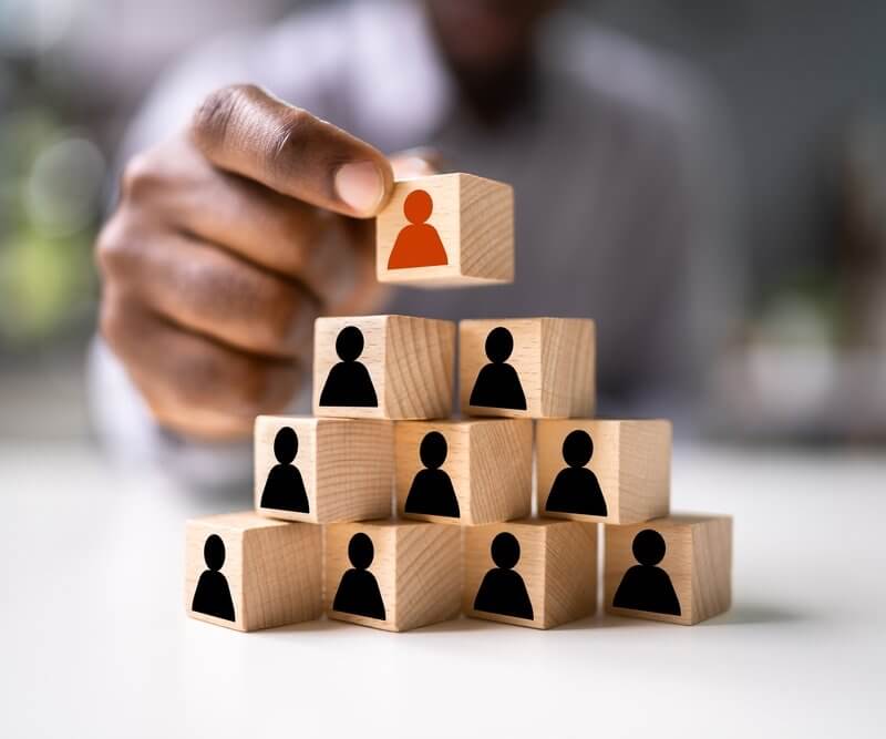 A person holds wooden cubes featuring illustrations of people, representing Capital Premium Financing's community focus.