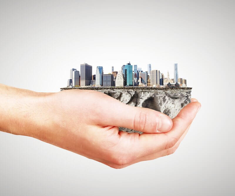 A hand holds a small city, illustrating the nurturing aspect of Capital Premium Financing in fostering urban growth and innovation.