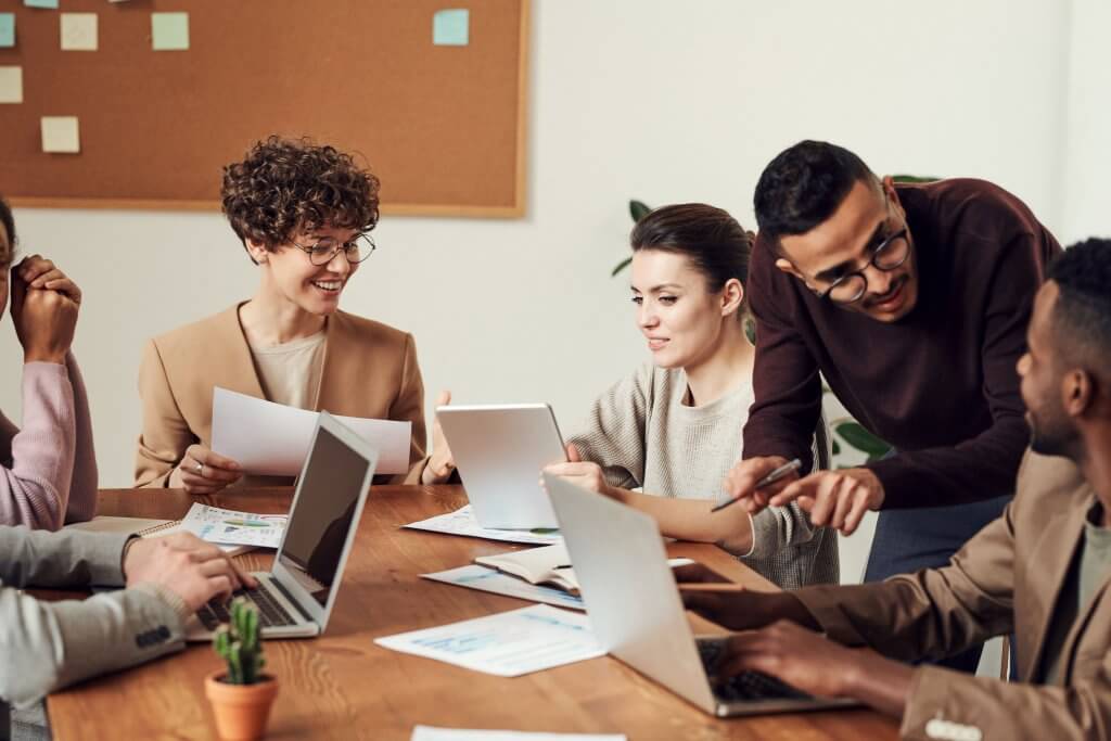 A diverse group of professionals collaborating around a table, each using laptops, representing Capital Premium Financing.