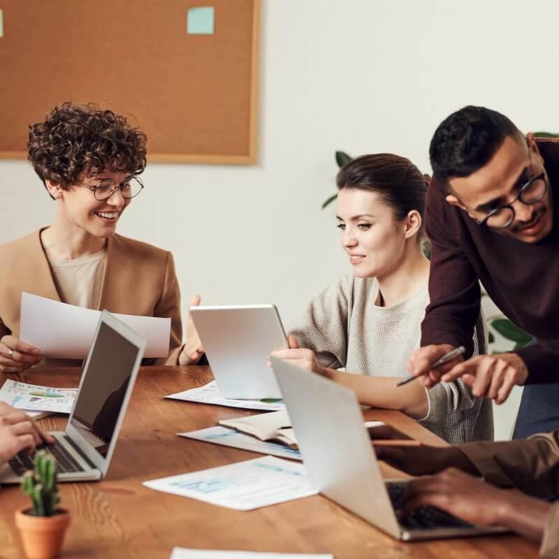 A diverse group of professionals collaborating around a table, each using laptops, representing Capital Premium Financing.