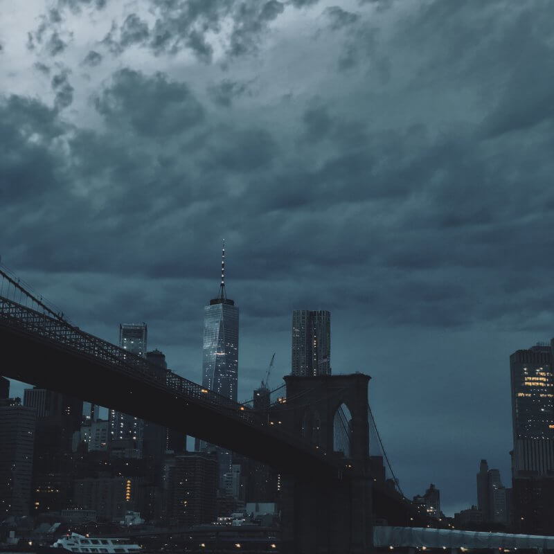 A cloudy sky looms over the iconic Brooklyn Bridge, symbolizing resilience and connection in urban landscapes.