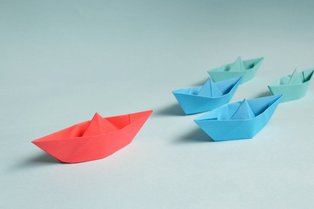 Four paper boats lined up in a row, symbolizing creativity and teamwork, representing Capital Premium Financing.