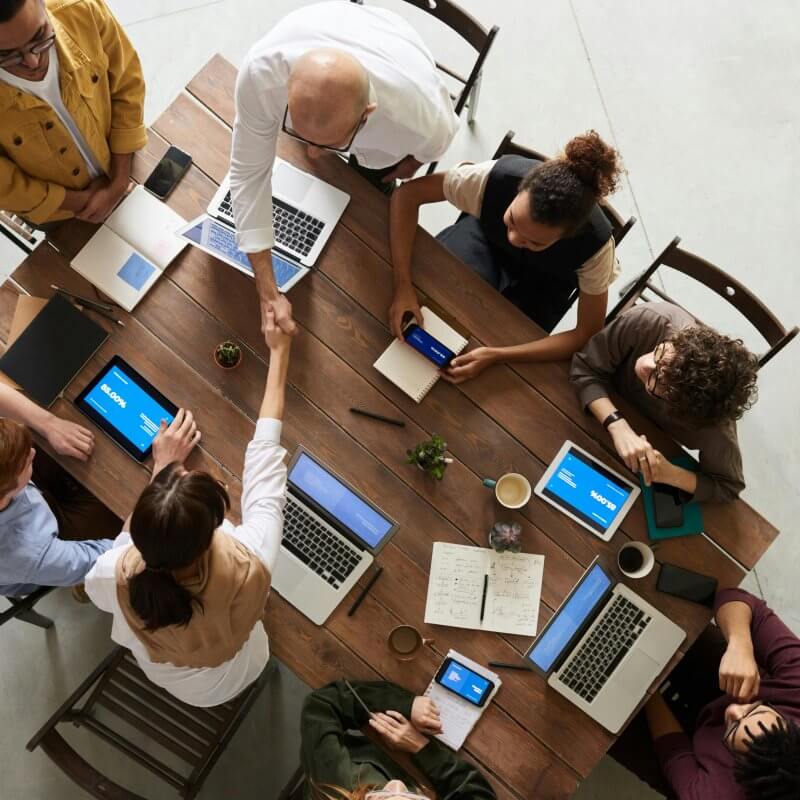 Individuals from Capital Premium Financing engaged in discussion while seated at a table with their laptops.