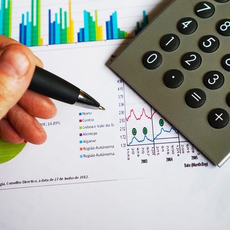 Individual using a calculator to analyze financial data related to Capital Premium Financing