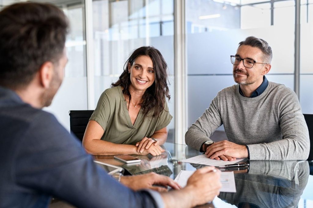 A man and woman collaborate on a project at a table in an office