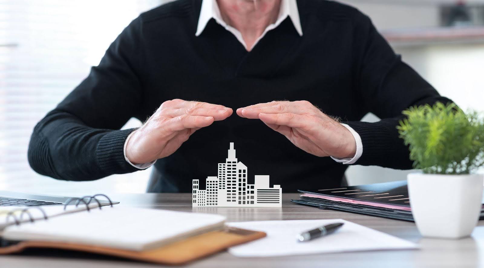 A man holds a detailed paper model of a city, illustrating various structures and urban layouts