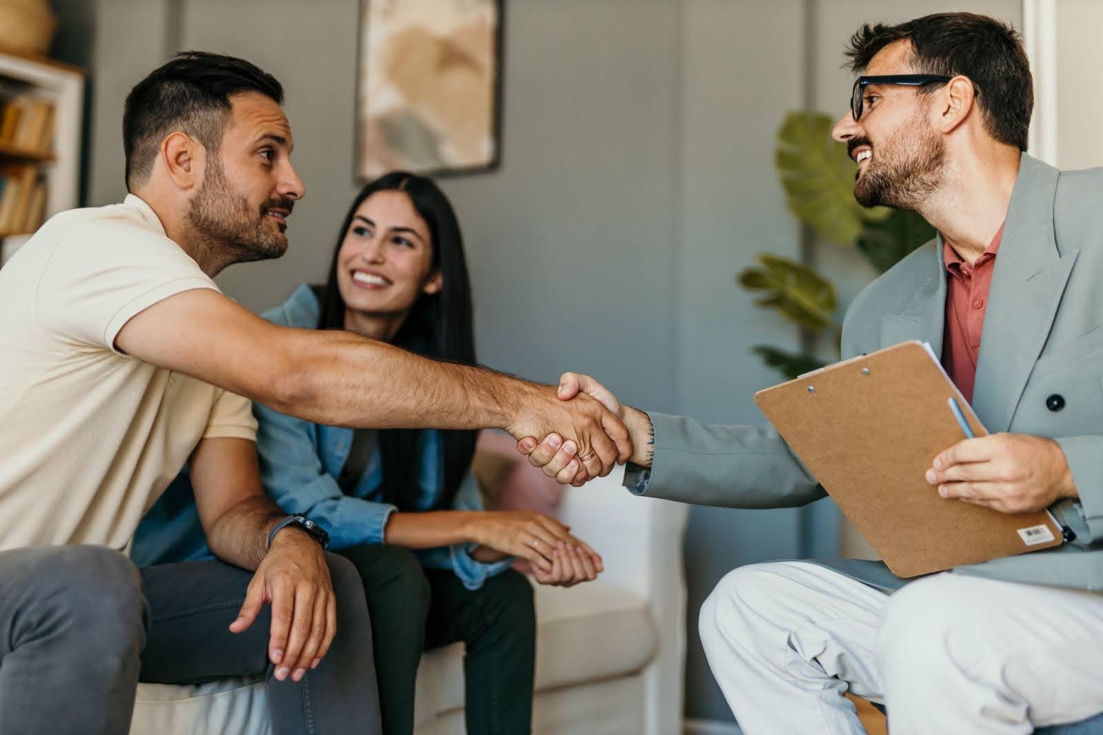 Two people shake hands with a man in a suit, signifying a business agreement or partnership