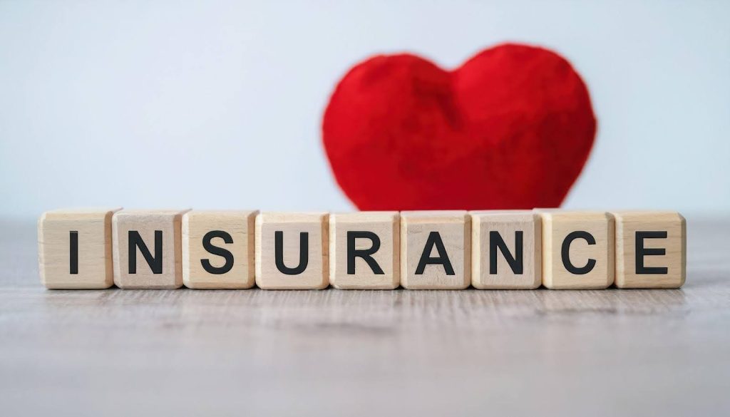 The word insurance with a heart symbol on a red block highlighting care and protection