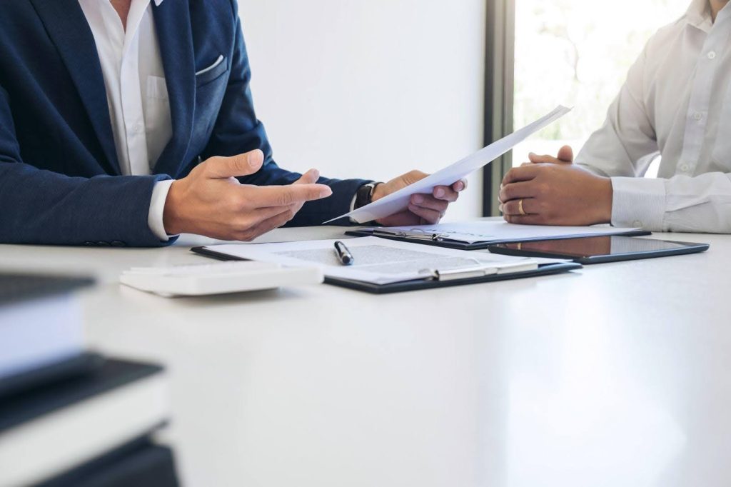 Two colleagues sitting at a table analyzing paperwork and collaborating on a project