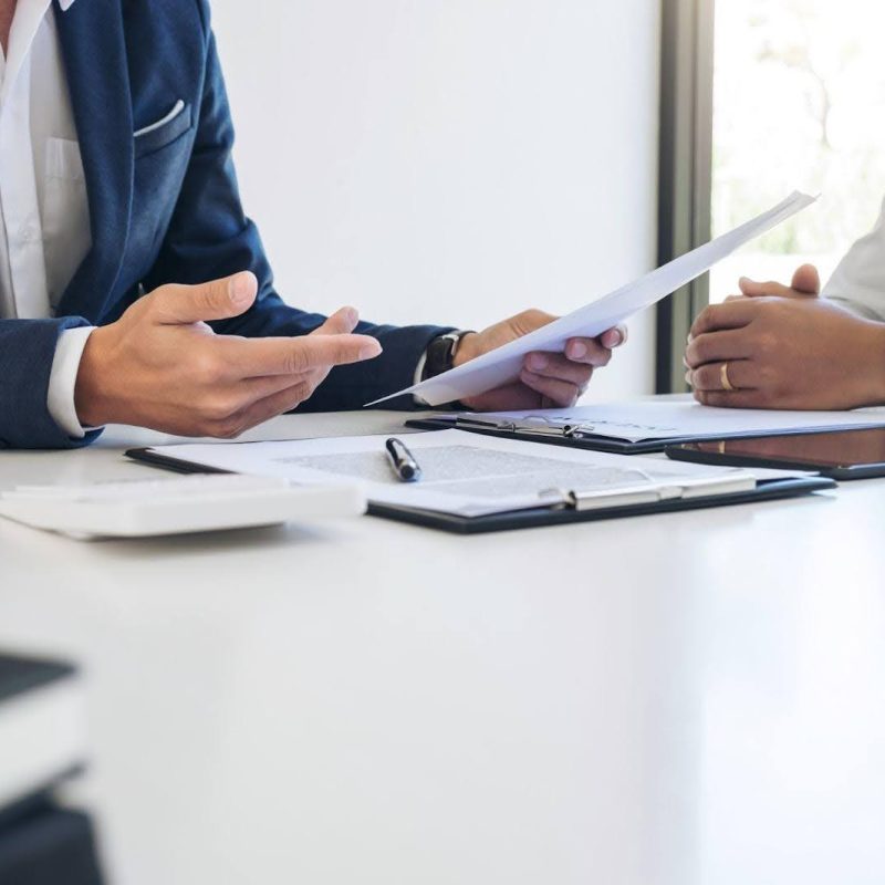 Two colleagues sitting at a table analyzing paperwork and collaborating on a project