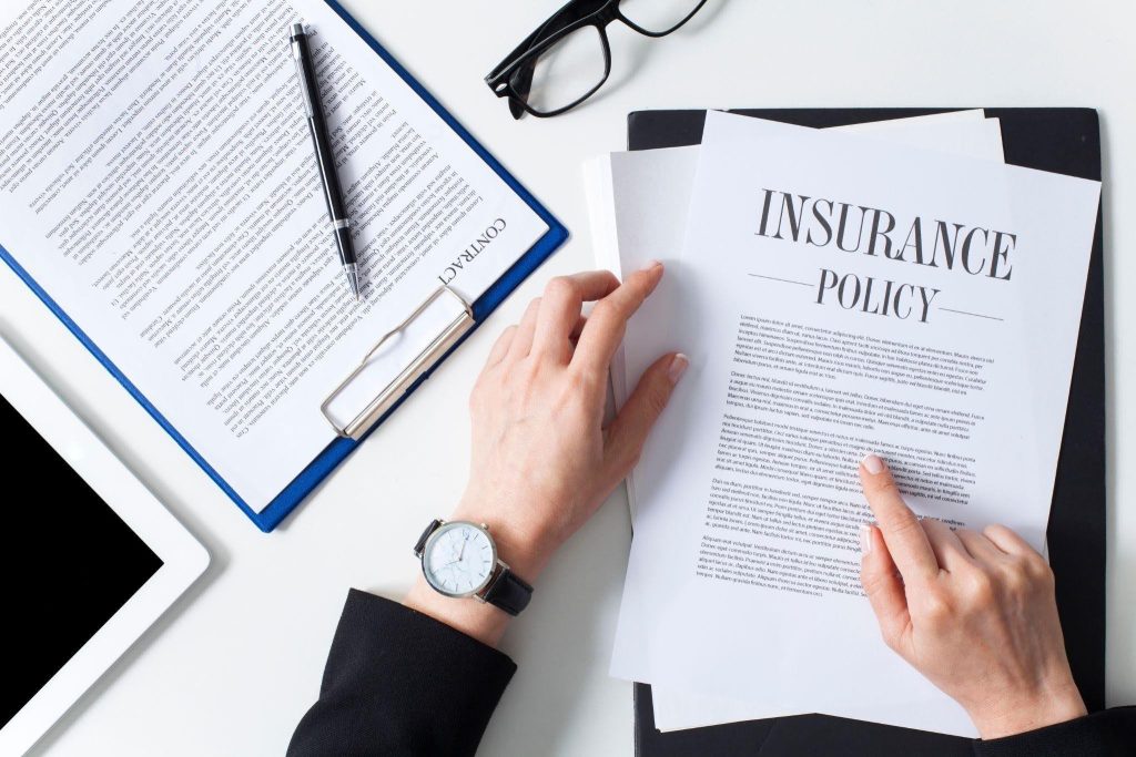 Hands displaying a folded insurance policy on a tabletop