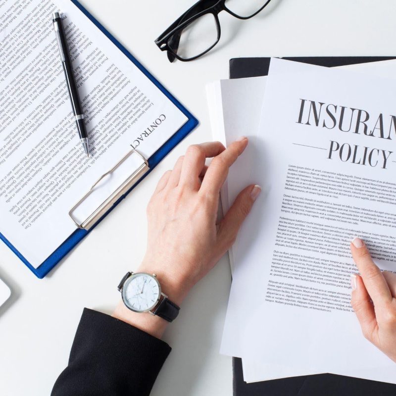 Hands displaying a folded insurance policy on a tabletop