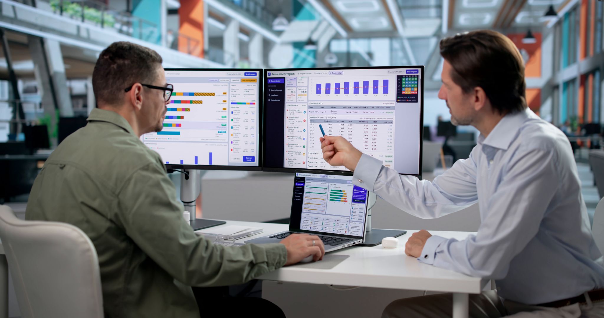 Two professional men analyzing financial data dashboards on dual computer monitors in a modern office.